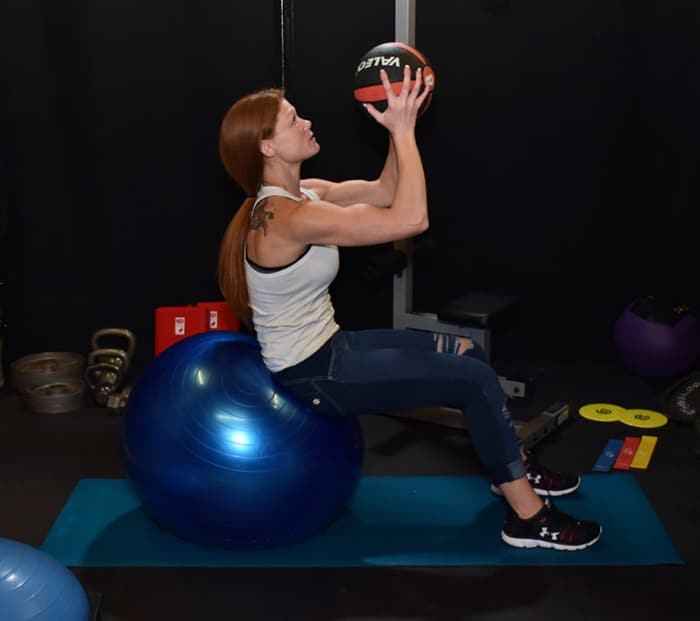 Michelle in profile demonstrating a seated ball lift.