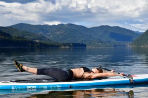 Train hard! Toned woman doing abdominal crunches on a SUP paddle board